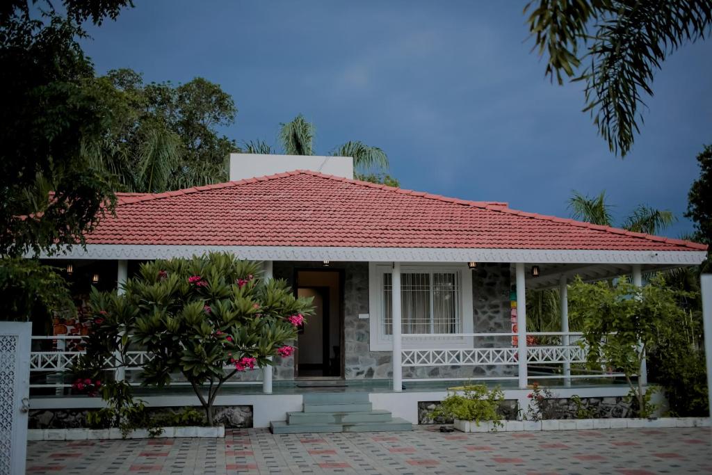 een klein wit huis met een rood dak bij The Native Place Shirdi in Shāhājāpur
