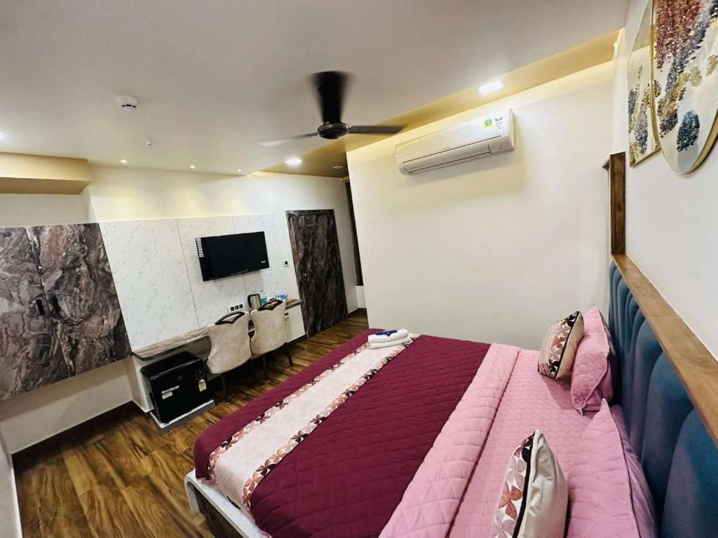a bedroom with a bed and a flat screen tv at HOTEL E CLASSICO in Bhavnagar