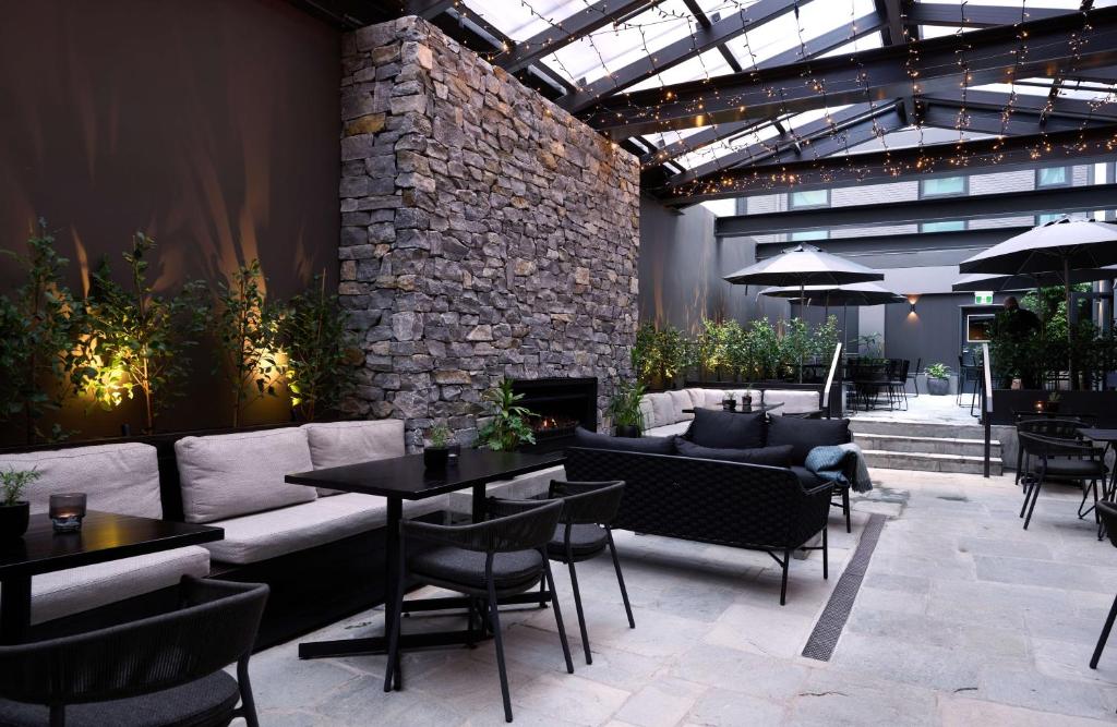a patio with a couch and tables and a fireplace at Abstract Hotel & Residences in Auckland