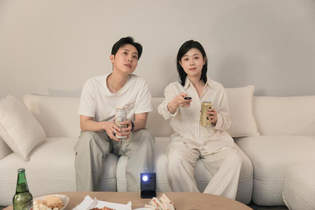 um homem e uma mulher sentados num sofá com bebidas em Aank Hotel Incheon Guwol em Incheon