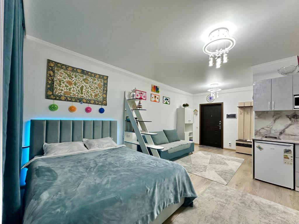 ein Schlafzimmer mit einem Bett und einem Stuhl sowie eine Küche in der Unterkunft Raduga West 'Azure' Apartment in Koshkolʼ