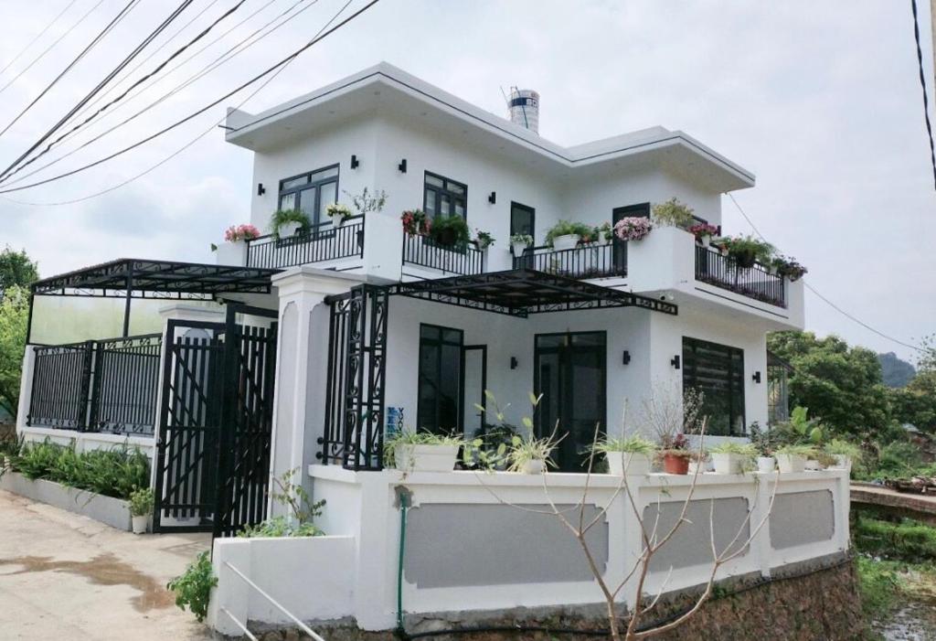 une maison blanche avec des plantes sur les balcons dans l'établissement TEELAD VILLA - MỘC CHÂU, à Mộc Châu