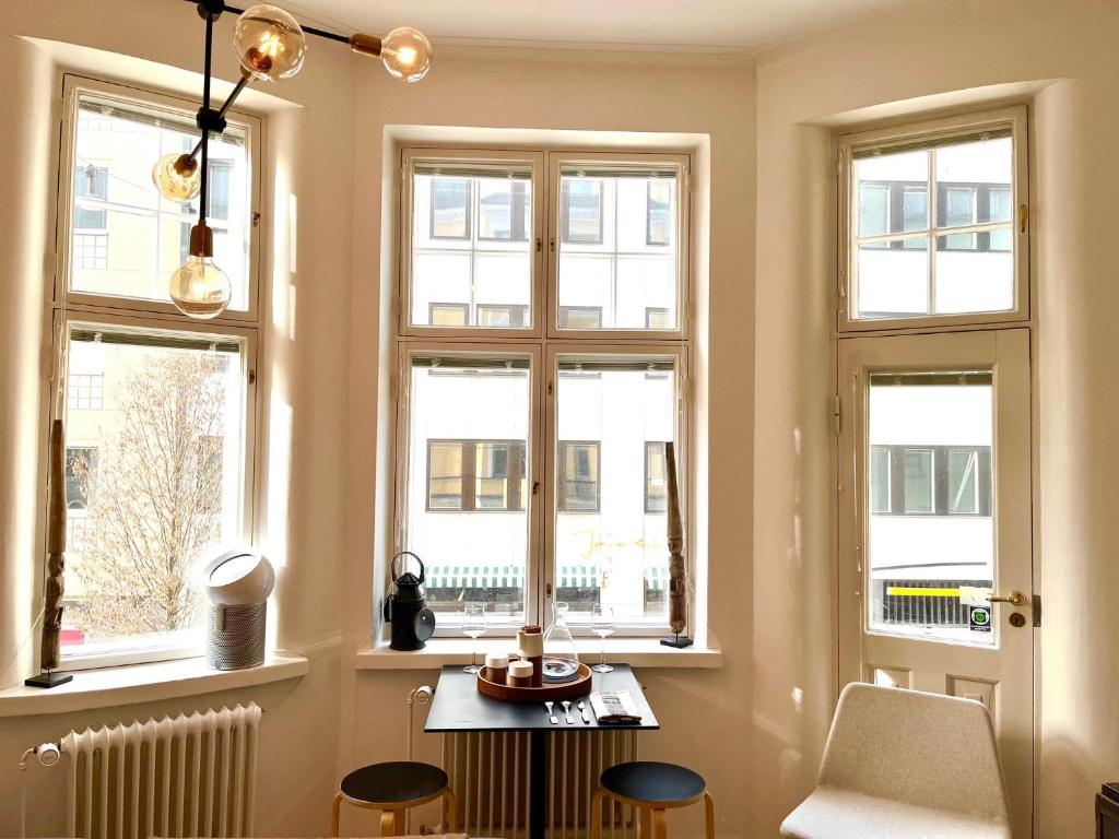 una camera con finestre, tavolo e sedie di Art Nouveau - Jugend Talo in Helsinki Center Apartment a Helsinki