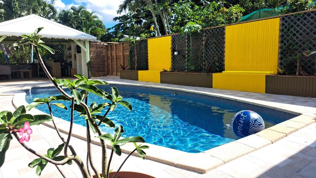 einen Pool in einem Garten mit einem gelben Zaun in der Unterkunft La libellule caribéenne in Sainte-Rose