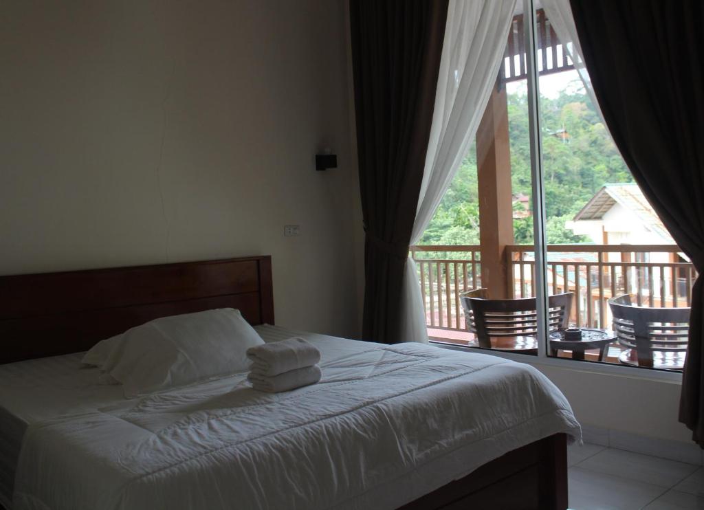 1 dormitorio con 1 cama con toallas y balcón en Jungle Treking In Bukit Lawang Booking with us, en Timbanglawang