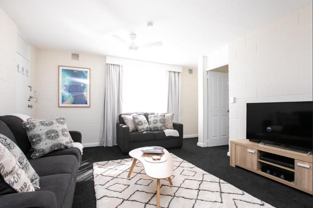sala de estar con 2 sofás y TV en CBD Apartment by the Park: WiFi & Parking en Launceston