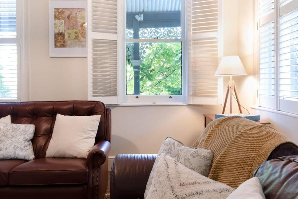 sala de estar con sofá de cuero y ventana en Charming On Charles, en Launceston