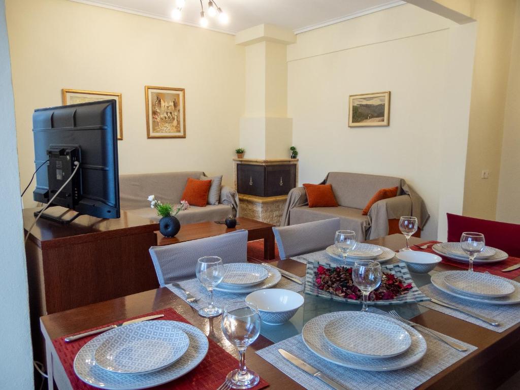 un comedor con una mesa con platos y copas de vino en The fir trees house - Το σπίτι με τα έλατα, en Litóchoron