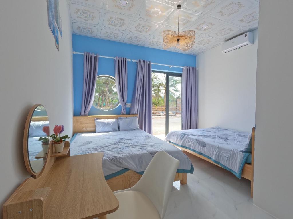 una camera con due letti, un tavolo e uno specchio di Homestay Đảo Phú Quý-White Sand House a Cu Lao Thu