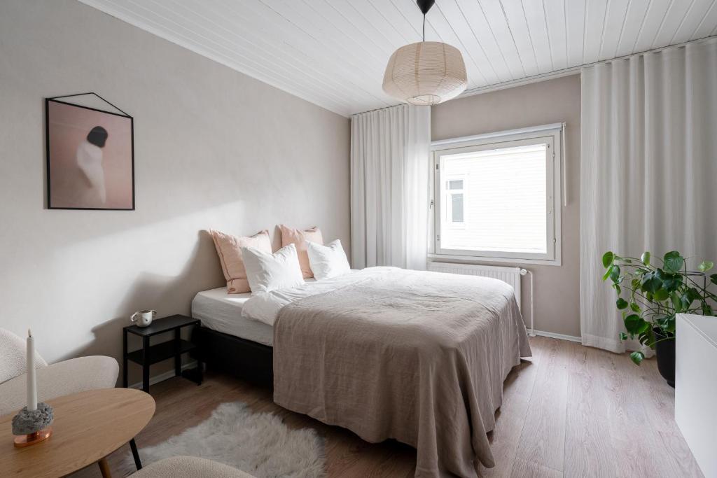 a white bedroom with a bed and a window at Lovely Studio in Pispala in Tampere
