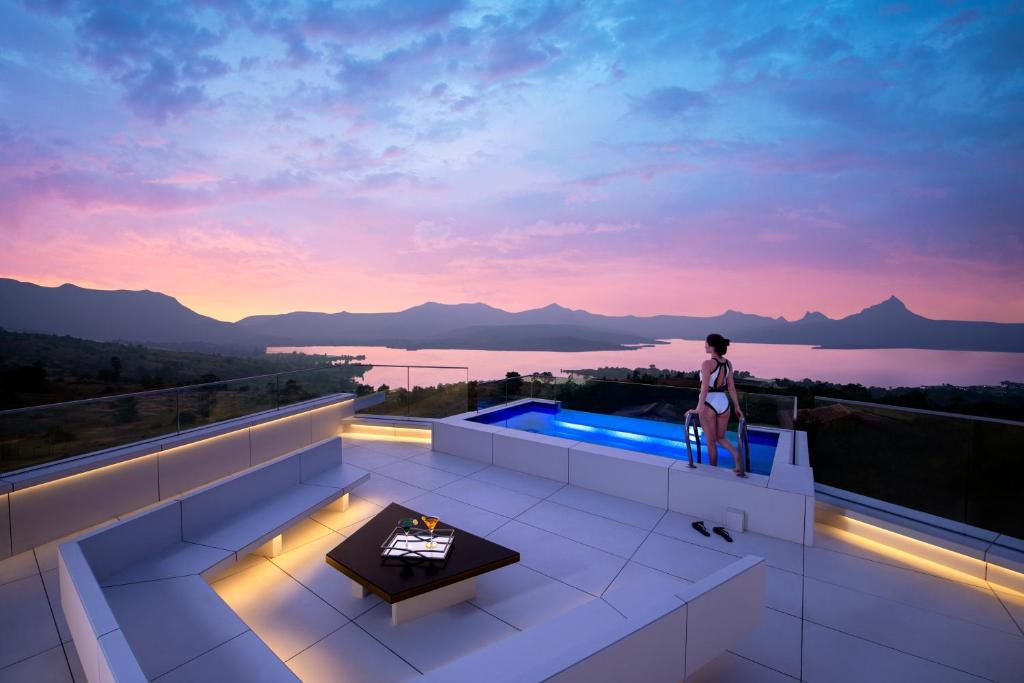 a woman standing on the balcony of a house with a view at Resort Amanzi in Lonavala