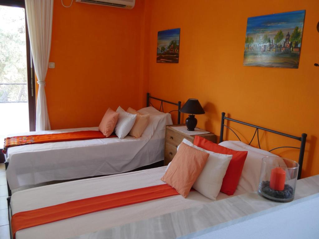 2 camas en una habitación con paredes de color naranja en Helios Rhodos Apartments 1 en Koskinou