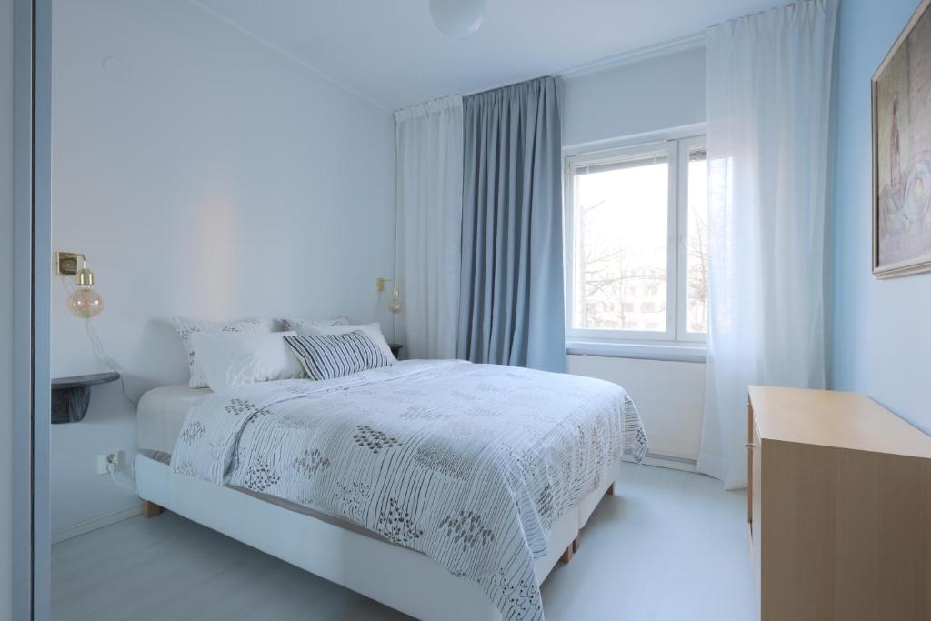 a white bedroom with a bed and a window at Urban Oasis - Two Bedrooms - Balcony - Nearby Metro in Helsinki