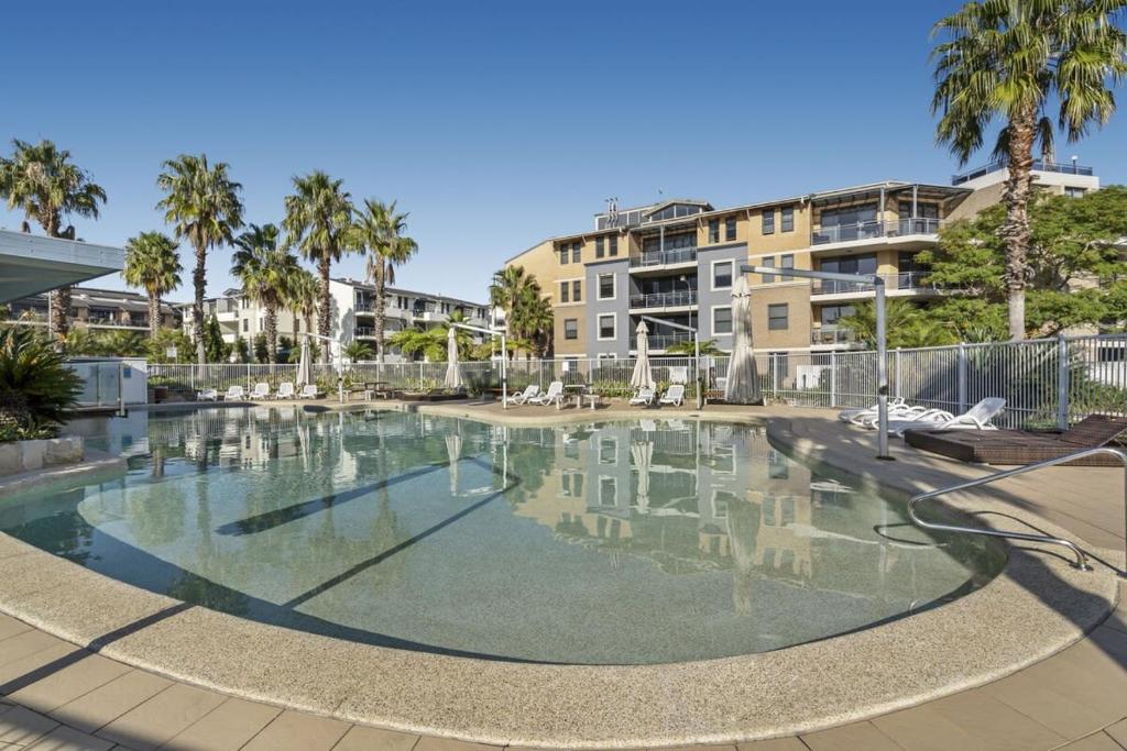 an empty swimming pool with palm trees and buildings at Gorgeous 2-Bed Unit near Riverside Parks in Sydney