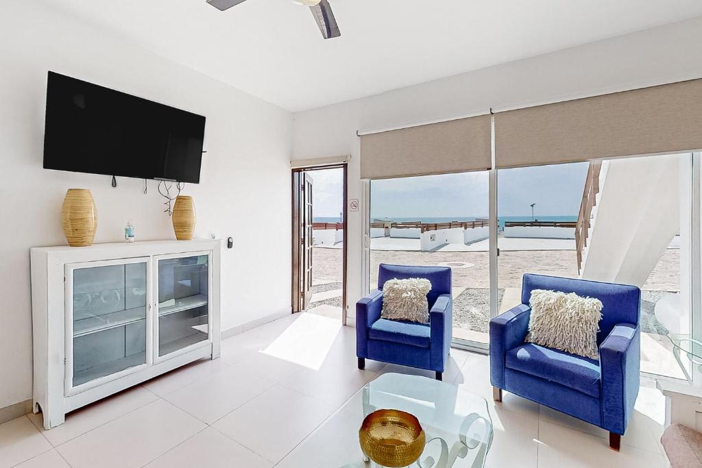 ein Wohnzimmer mit 2 blauen Stühlen und einem TV in der Unterkunft Casa Capri 39 - Playa Arcangel in Rosarito