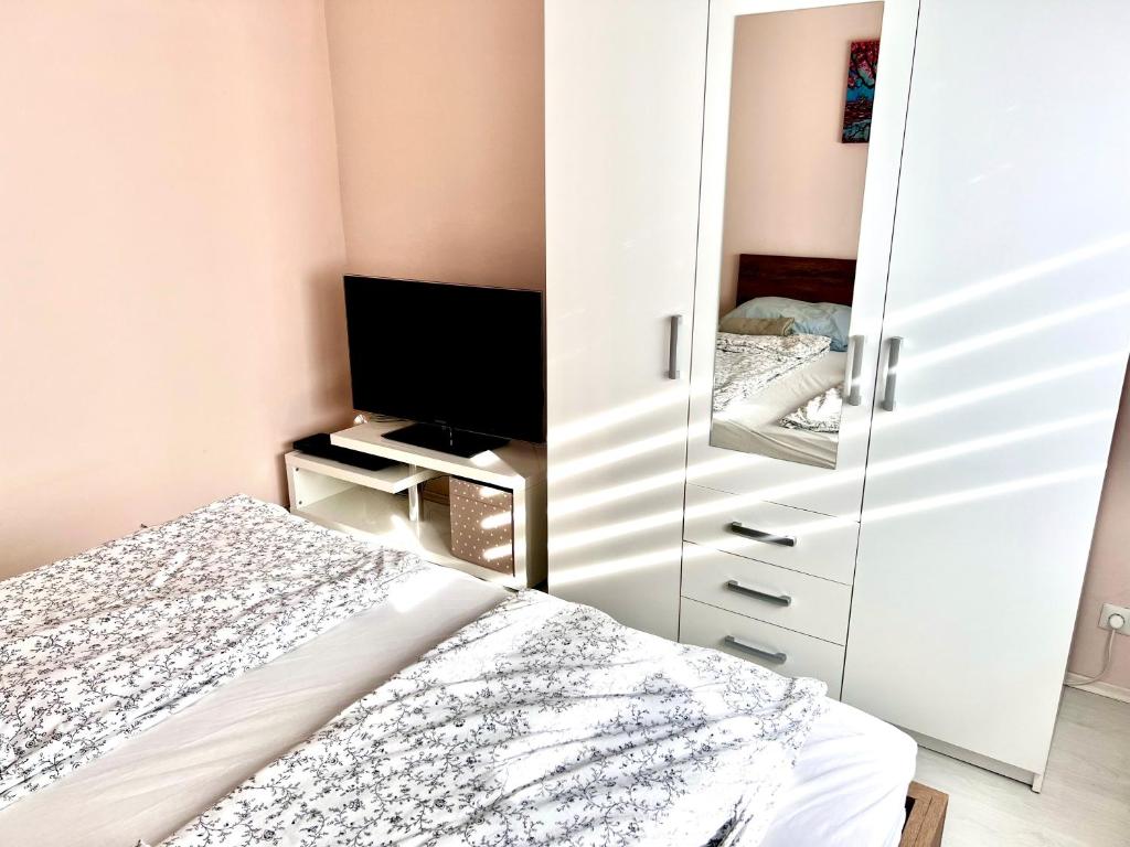 a bedroom with a mirror and a bed and a television at HUN-HON Apartman in Tiszaújváros