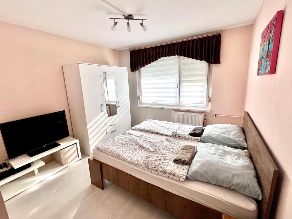 a bedroom with a bed and a flat screen tv at HUN-HON Apartman in Tiszaújváros