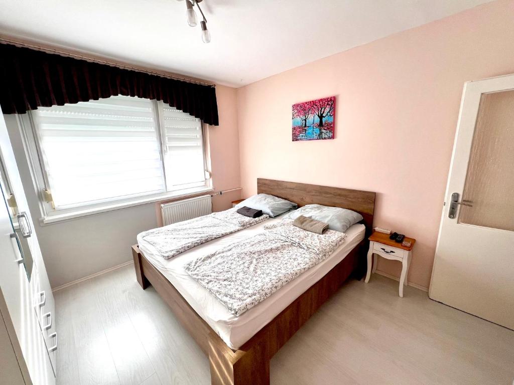 a bedroom with a bed and a window at HUN-HON Apartman in Tiszaújváros
