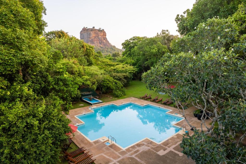 an overhead view of a swimming pool with a mountain in the background at Sigiriya Village in Sigiriya