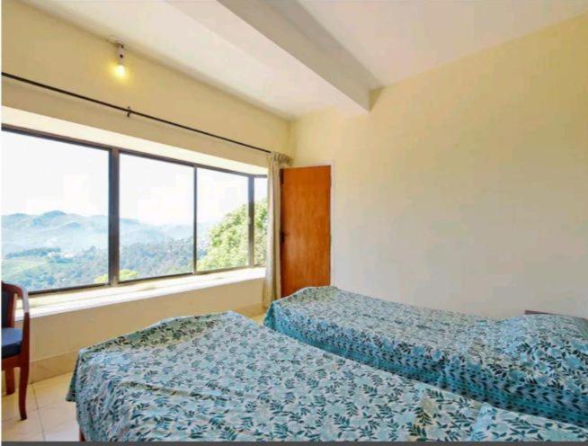 1 dormitorio con 2 camas y ventana grande en Camellia Heights 1&2, en Coonoor