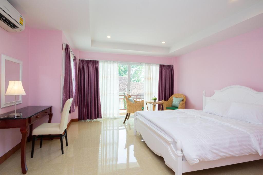 a bedroom with a white bed and a desk and a window at Takanta Place in Udon Thani