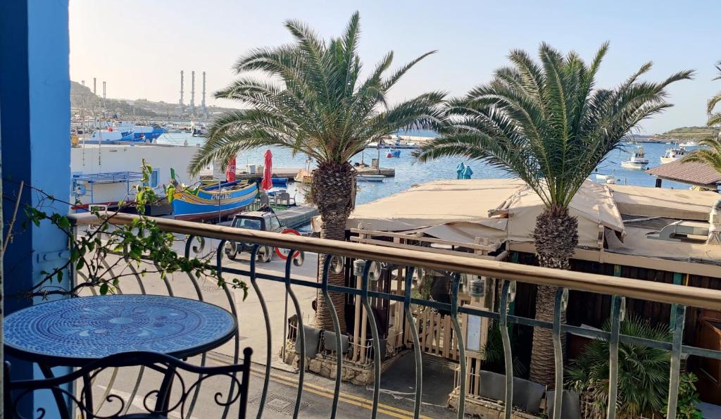 a balcony with palm trees and a marina with boats at Marsaxlokk Sea View in Marsaxlokk