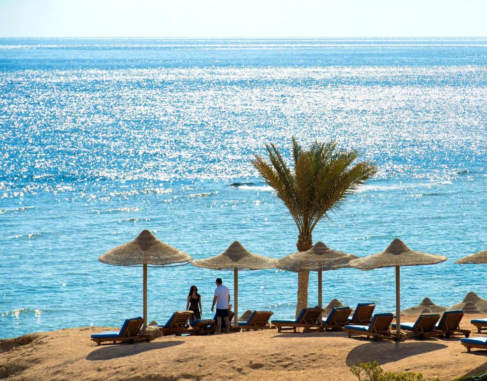 een groep mensen op een strand met parasols bij Charmillion Club Resort in Sharm El Sheikh