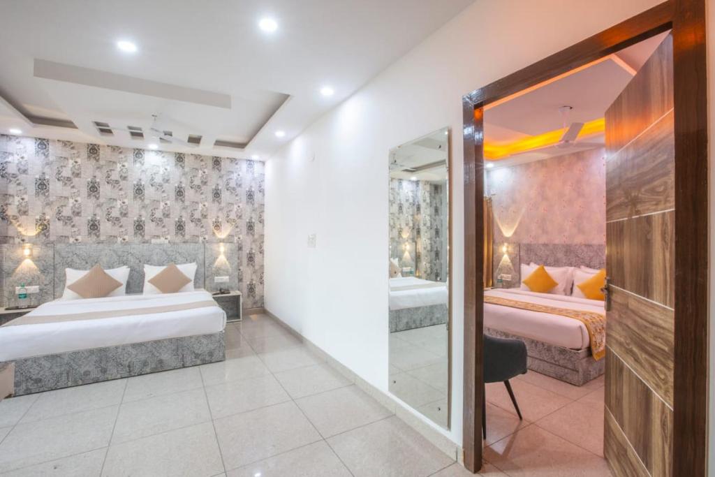Habitación de hotel con 2 camas y espejo en Airport Grand Travel Inn, en Nueva Delhi