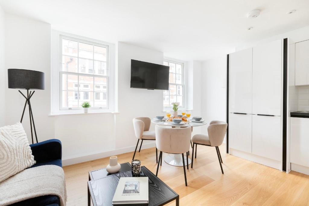 a white living room with a table and chairs at Soho & Fitzrovia with Balcony - CityApartmentStay in London