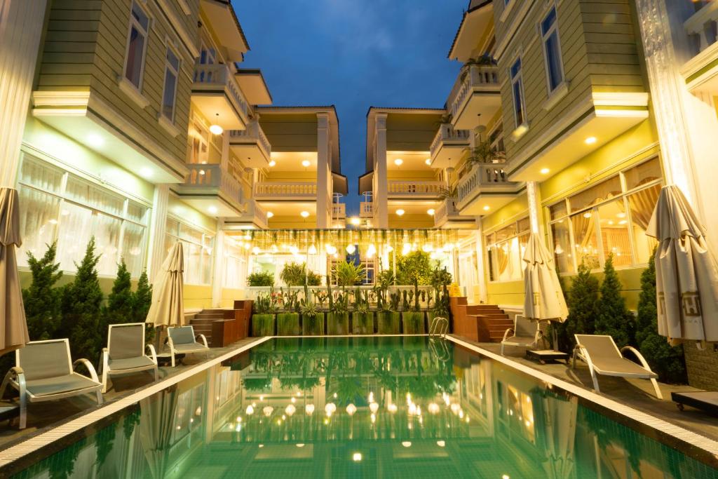 a hotel pool with chairs and umbrellas at Hawal Boutique Villa Hoi An in Hoi An