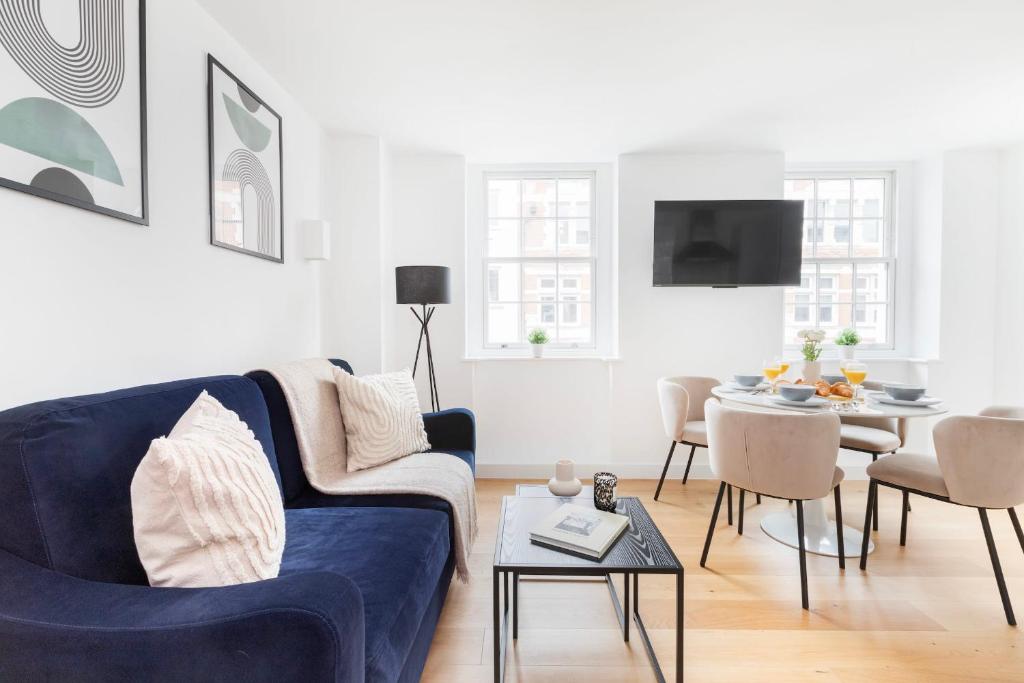 a living room with a blue couch and a table at Fitzrovia with Balcony - CityApartmentStay in London