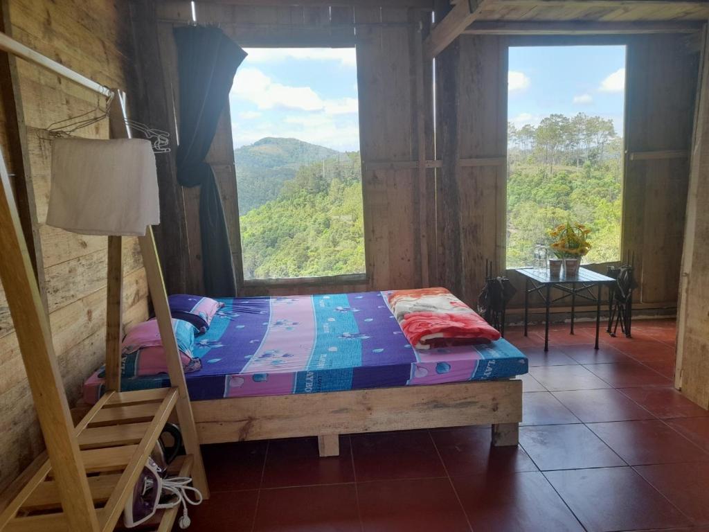 een slaapkamer met een bed en een groot raam bij Homestay niem t'rị Măng Pên in Kon Von Kla