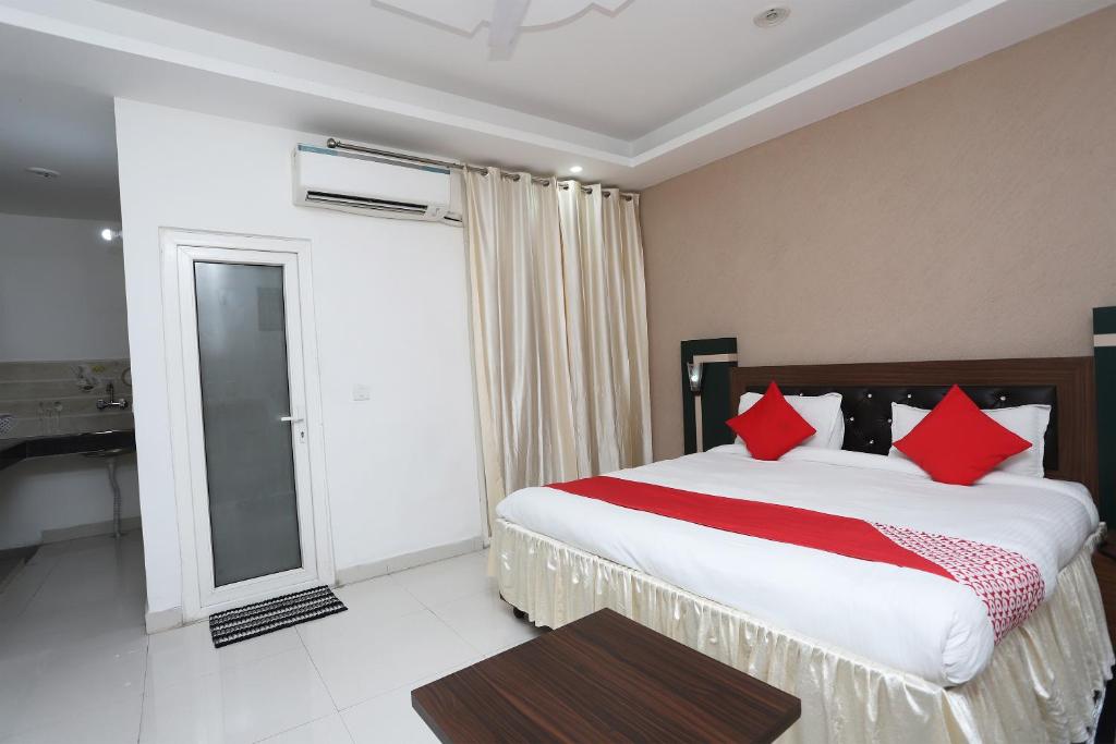 - une chambre avec un grand lit et des oreillers rouges dans l'établissement Super Capital O Hotel Levanti Near Aravali Biodiversity Park, à Gurgaon