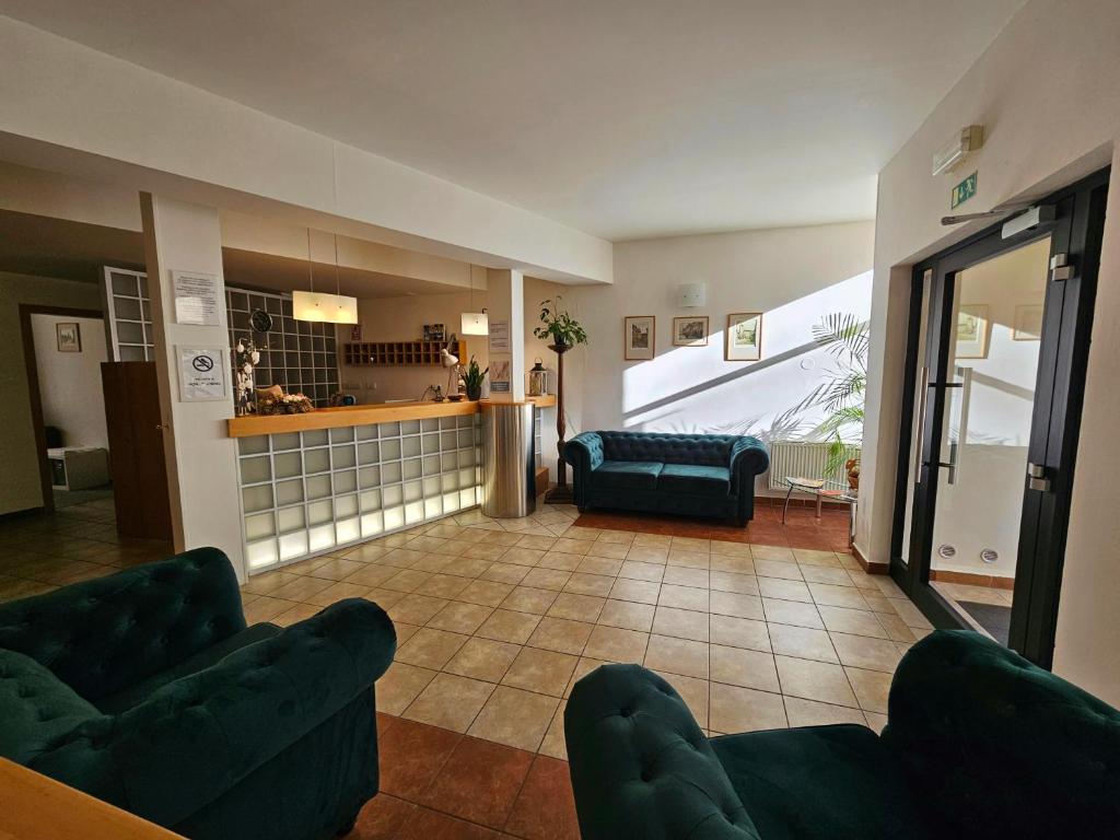 a living room with two green couches and a kitchen at Hotel Claris in Prague