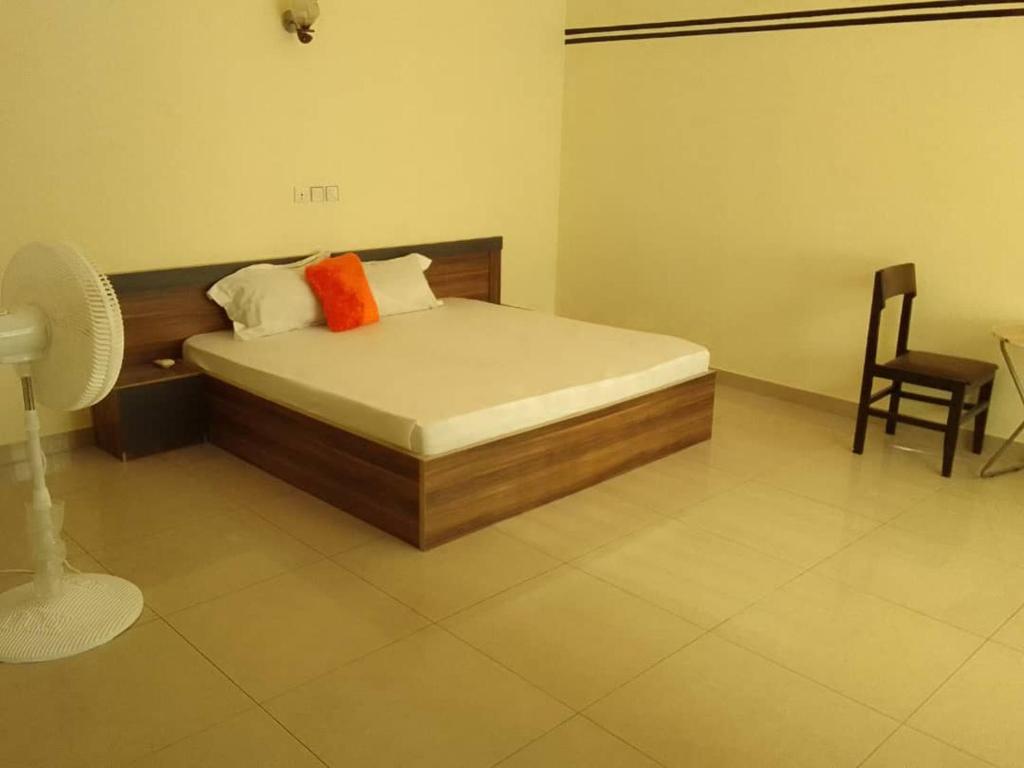 Un dormitorio con una cama con una almohada naranja y una silla en HOUSE SOS, en Abomey-Calavi