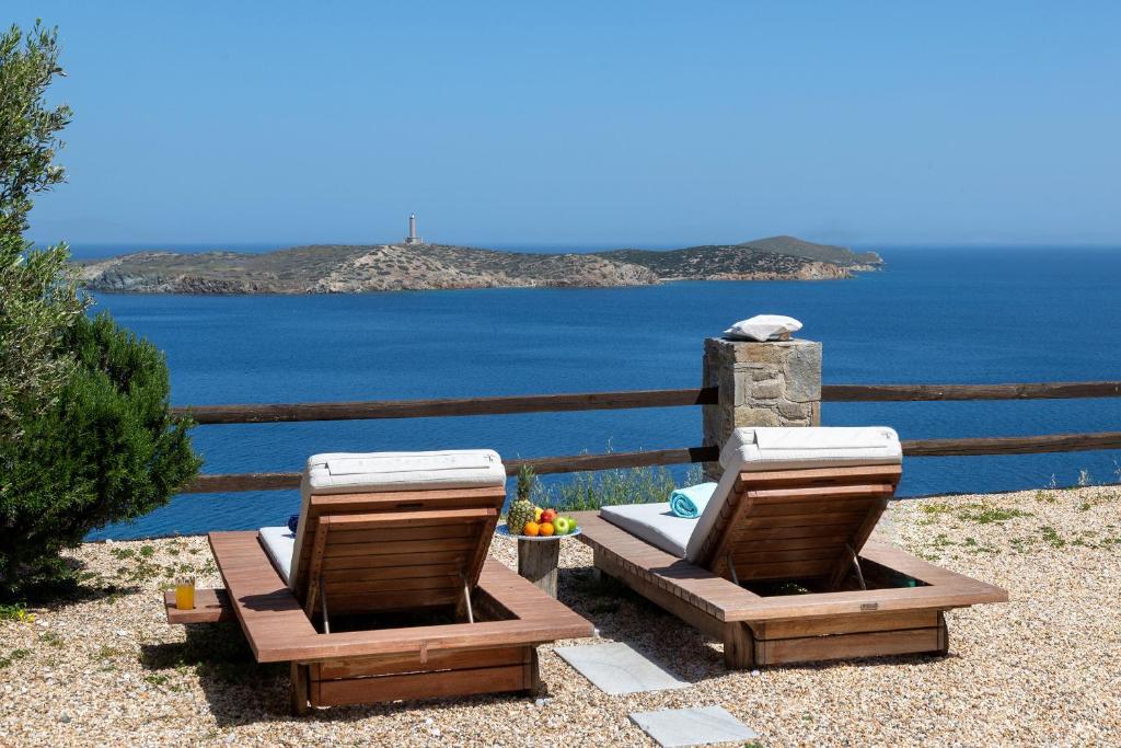 two lounge chairs sitting next to the ocean at Aegean View - Seaside Apartment in Syros in Azolimnos