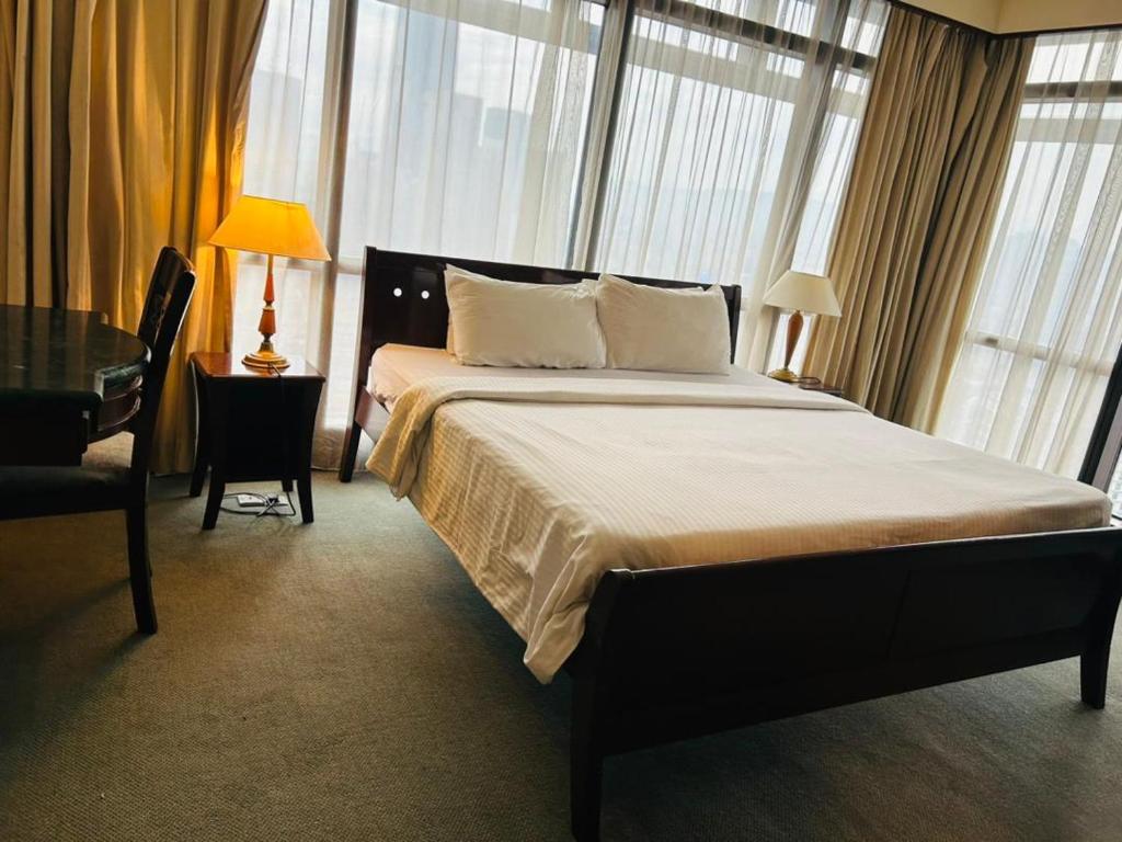 um quarto com uma cama grande num quarto com janelas em SAMI APARTMENT - Times Square KL em Kuala Lumpur