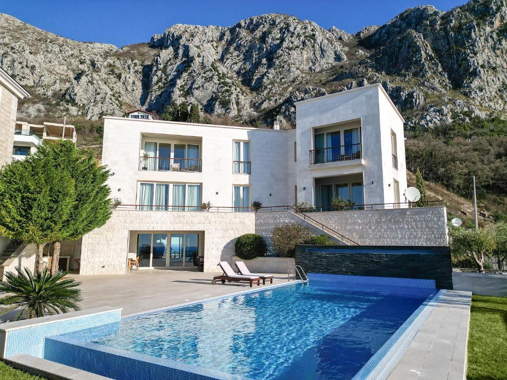 una casa con piscina frente a una montaña en Villa Hedonism en Sveti Stefan