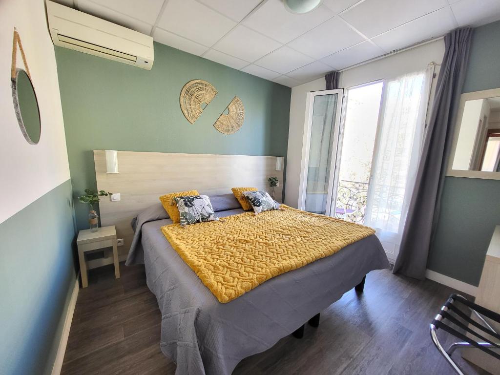 a bedroom with a bed and a large window at Hotel Parisien in Menton