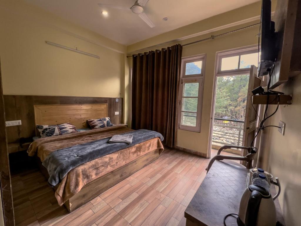 1 dormitorio con cama y ventana grande en Forest View by The Delhi Heights Kasol en Kasol