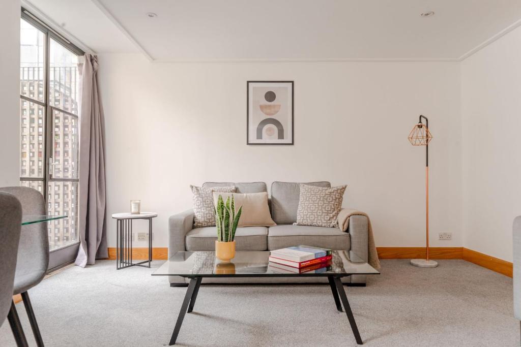 ein Wohnzimmer mit einem Sofa und einem Couchtisch in der Unterkunft Holborn - 2BR Near Covent Garden -CityApartmentStay in London