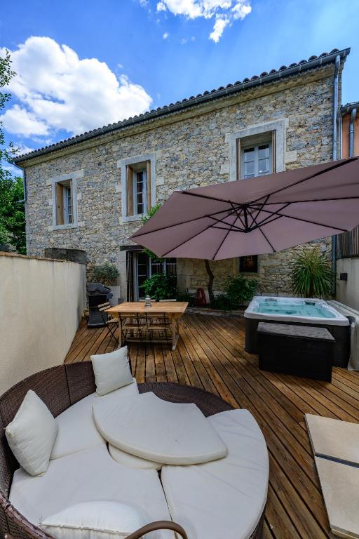 un patio avec un canapé et un parasol sur une terrasse en bois dans l'établissement Pietra Viva, à Les Matelles