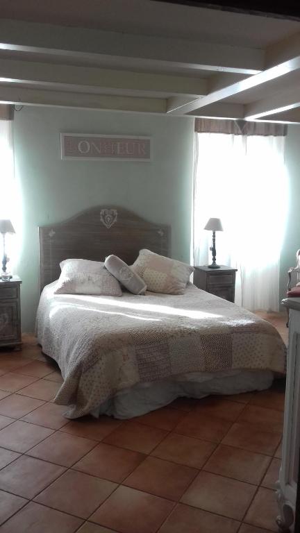 a bedroom with a bed with two lamps and two windows at B&B L'Avelan in La Trinité