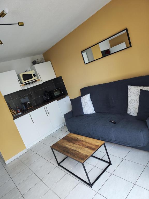 un salon avec un canapé bleu et une table basse dans l'établissement Agde Studio proche Plage, à Agde