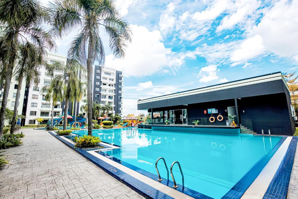 a large swimming pool with palm trees and a building at Manhattan Condominium Ipoh in Ipoh