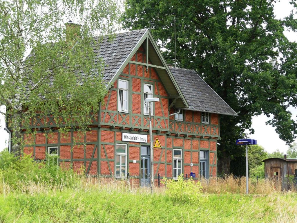 ein rotes Backsteingebäude mit schwarzem Dach in der Unterkunft Ferienwohnung Bahnhof 1892 in Meeder
