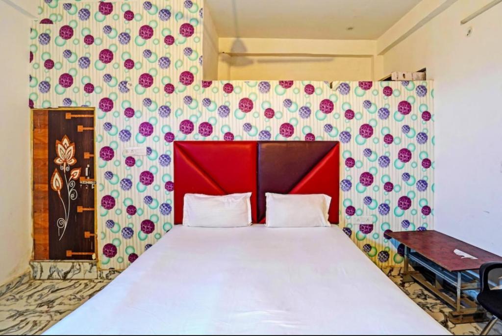 - une chambre avec un grand lit et une tête de lit rouge dans l'établissement VR HOTEL, à Auraiya