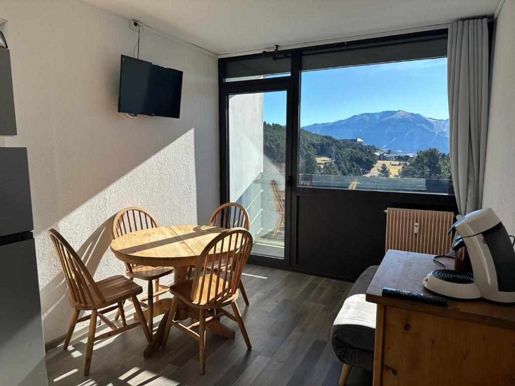 Cette chambre dispose d'une table et de chaises et offre une vue sur la montagne. dans l'établissement Font Romeu vue imprenable 2ch 6p, à Égat