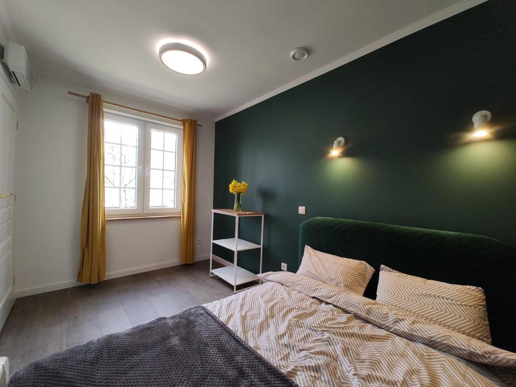 Dormitorio verde con cama y ventana en Dwie Chatki domek, en Sandomierz
