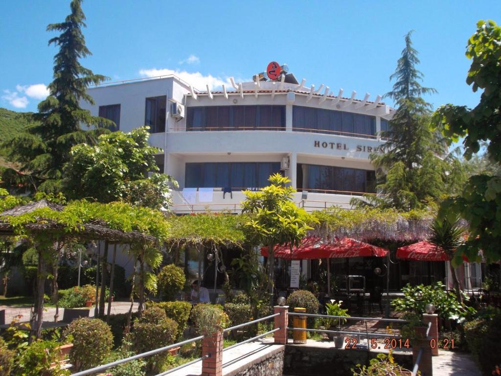 un hotel con muchos árboles delante de él en SIRENA HOTEL, en Tushemisht